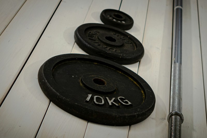 weights on white wooden floor witih barbell weight plates