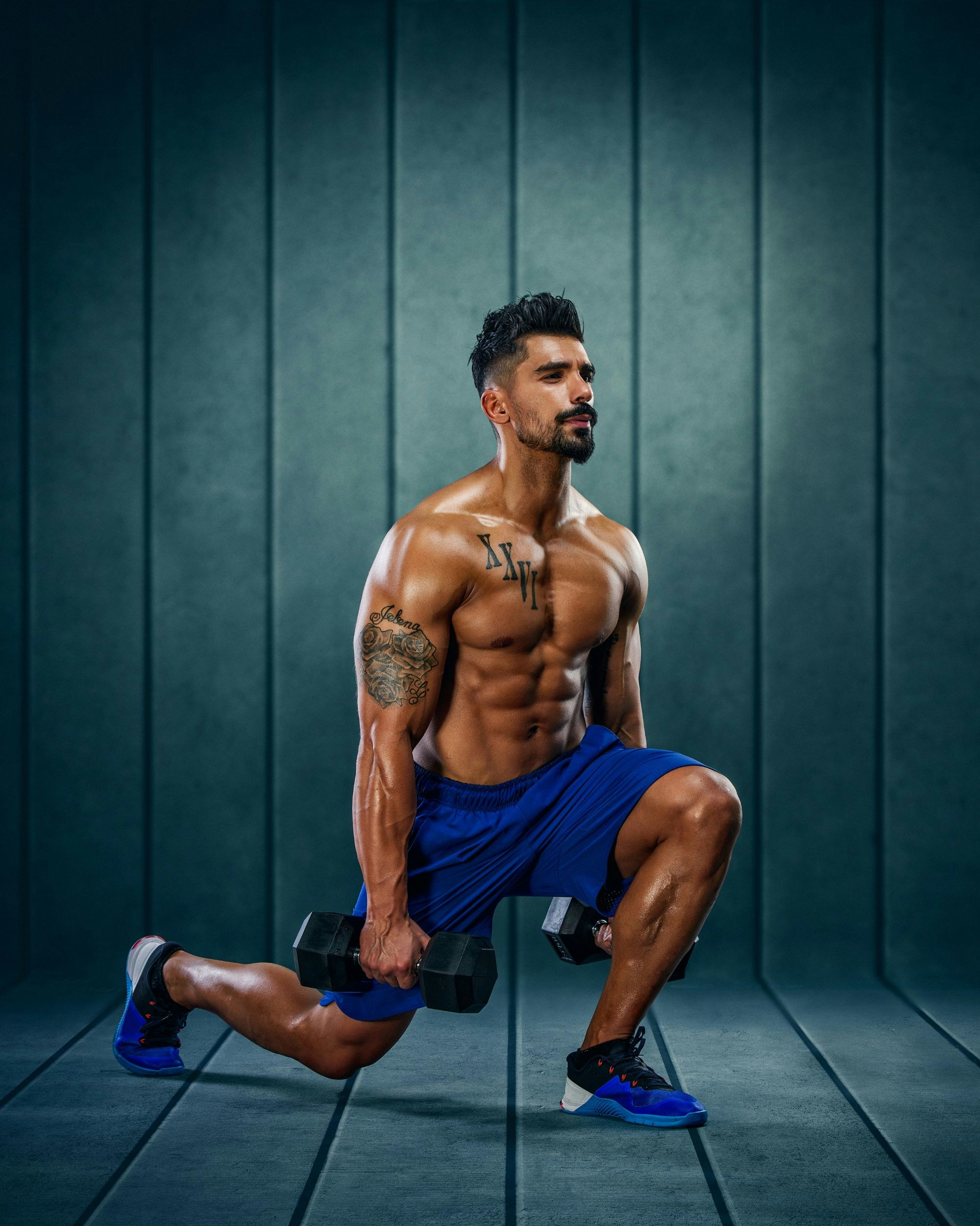 tanned man wering blue shorts blue sneakers doing dumbbell lunge shirtless-unsplash